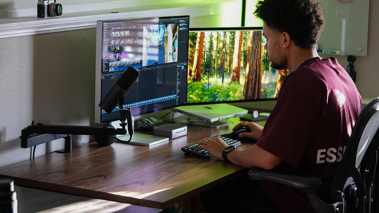 Mike editing a video at his desk with a camera, microphone, and dual monitors